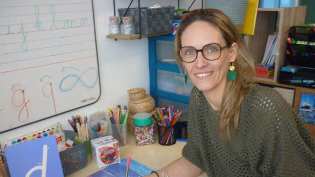 Sandrine Le Moelle, la graphothérapeute à son bureau tenant un crayon à la main